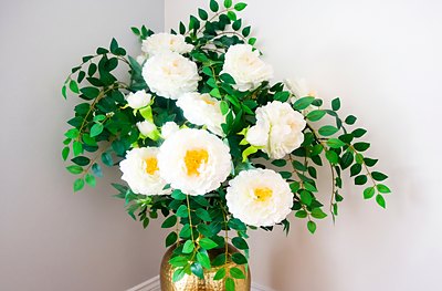 White peonies in a hammered gold vase, standing in a corner of the house.