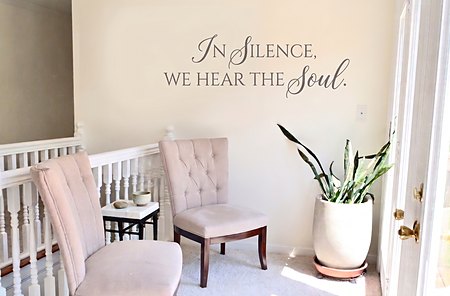 Two soft chairs on the landing by the deck doors, under the words In Silence, We Hear The Soul.