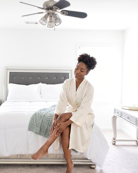 A guest in a robe sitting on the end of the bed in one of the suites, in morning light.