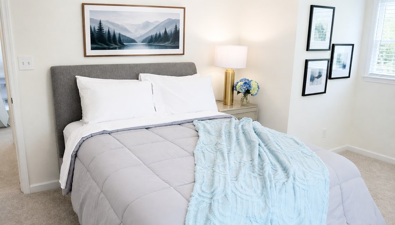 Amara Verde, the bed with its blue throw and a framed landscape hung above the headboard.