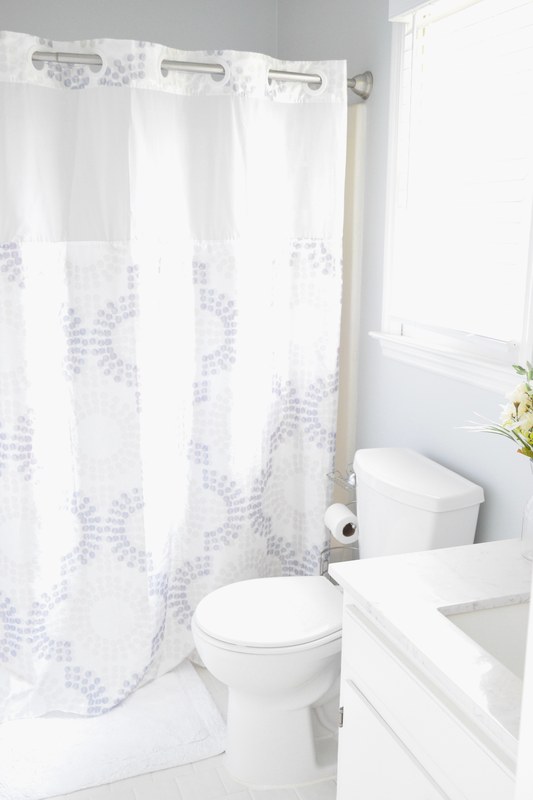 A bathroom with the shower, the toilet and a marble-topped vanity by the window.