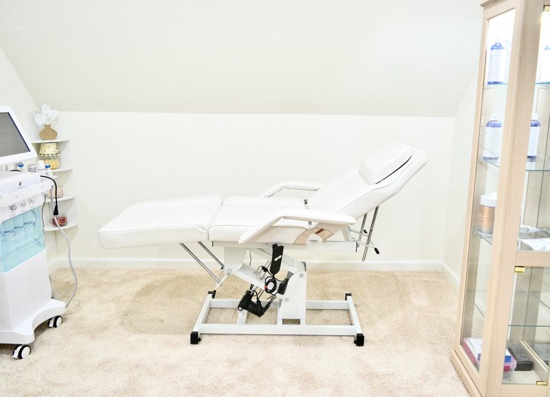 The treatment room, a white treatment chair under the sloped ceiling with a product cabinet beside it.