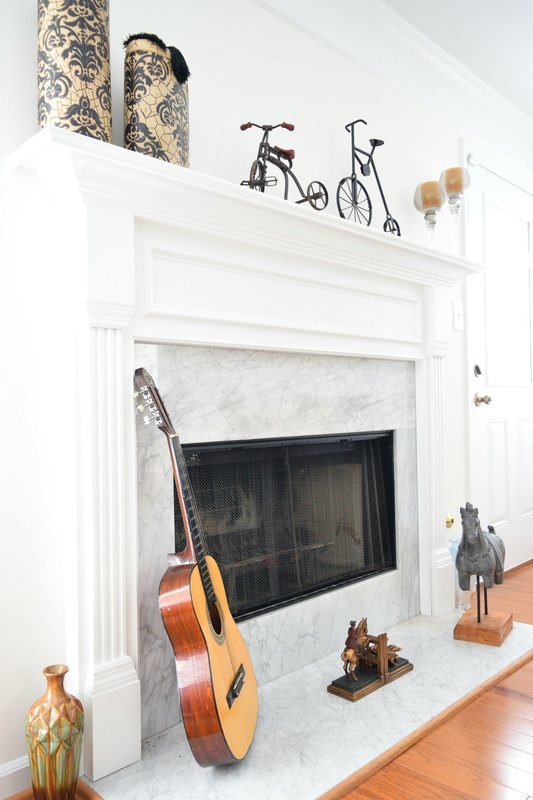 The living room fireplace, a white painted mantel over a marble surround.