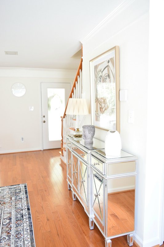 The entrance hall, with a mirrored console table and the staircase beyond.