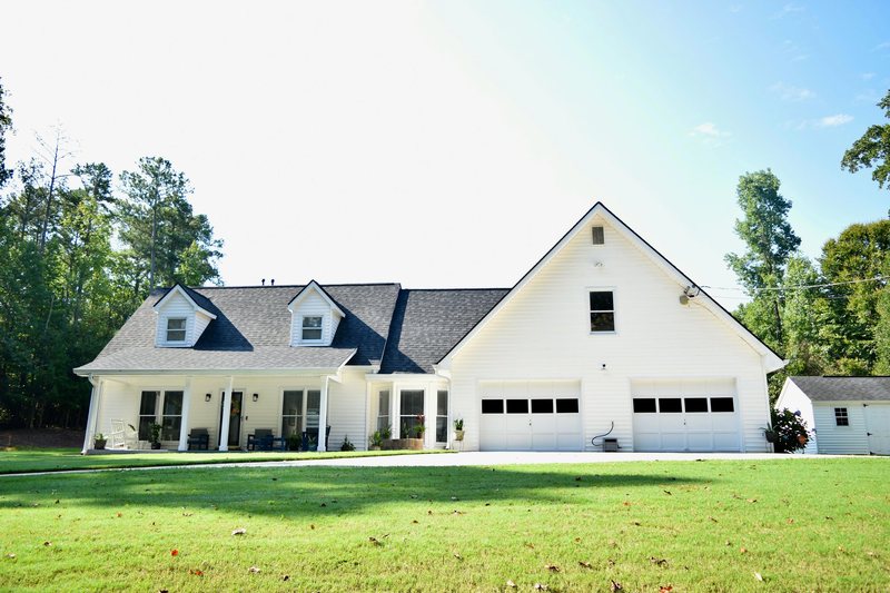 The front of the house from the lawn, with the porch furniture and the double garage.