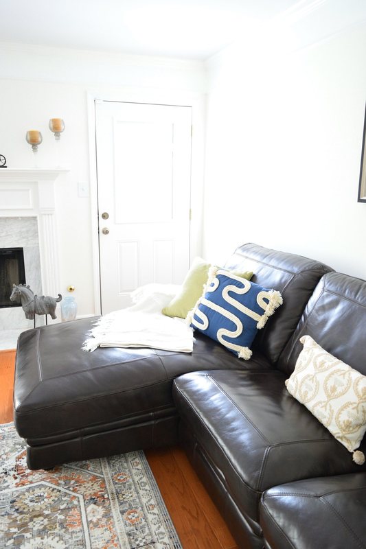 The corner of the living room, sectional and fireplace with the front door beside them.