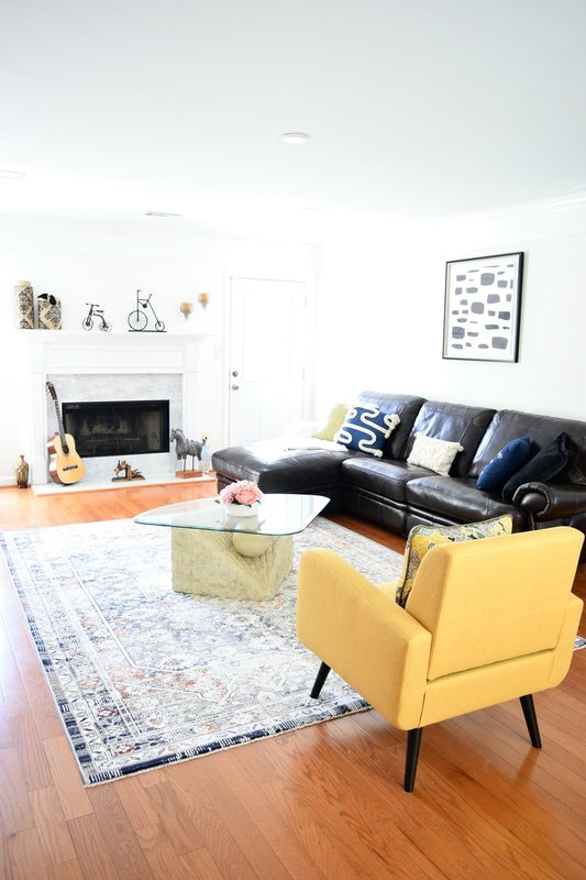 The living room, a leather sectional facing the fireplace with the dining room beyond.