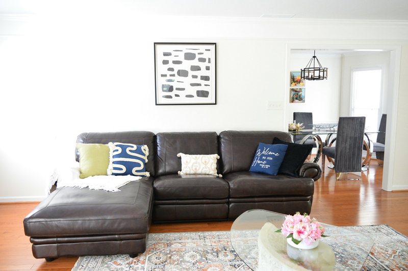 The living room from the side, sectional, patterned rug and framed art.