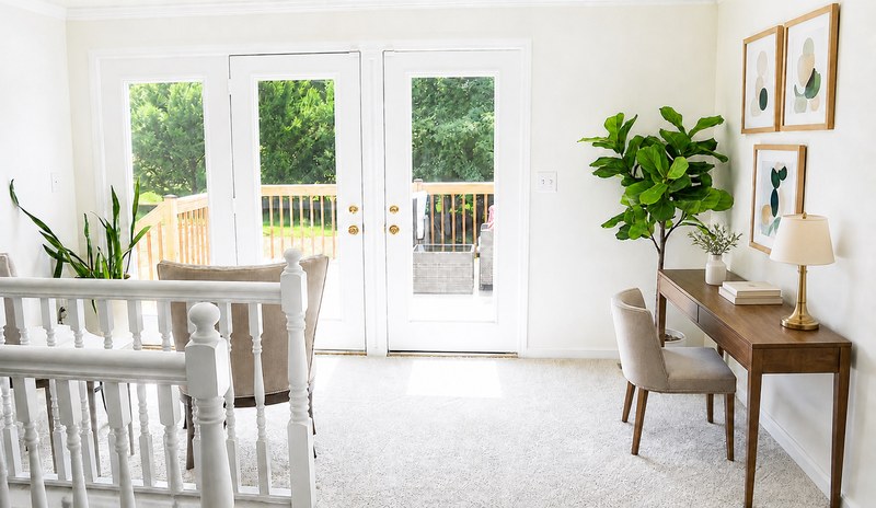 The French doors from the landing out onto the deck, a writing desk and a tall fig alongside the stair rail.