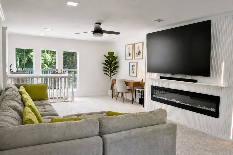 The upstairs lounge, the television above the fireplace and the sectional sofa with green cushions.