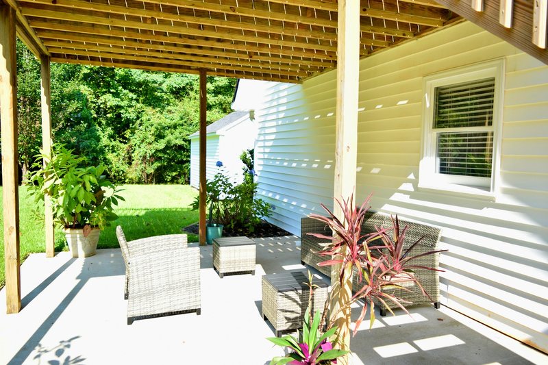 The patio under the deck, woven armchairs and planted pots.