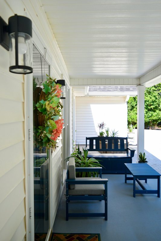 The covered front porch, with a seasonal wreath and a bench looking out.