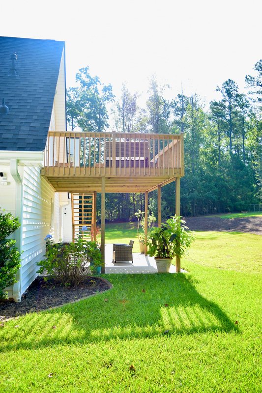 The raised deck at the back of the house, with the paved patio underneath it.