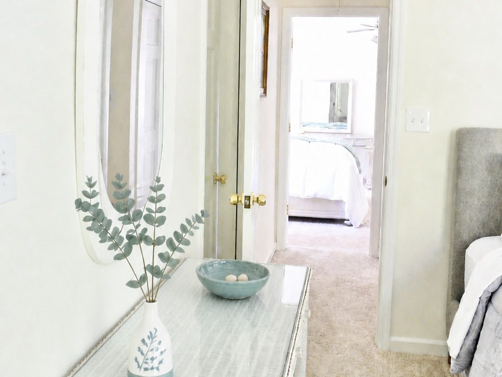 Amara Verde Suite: eucalyptus in a vase and a blue bowl on the vanity, with the door open to the landing beyond.